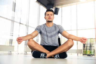 Portrait of a handsome man meditating in fitness gym